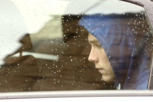 Sad teenager through rainy window